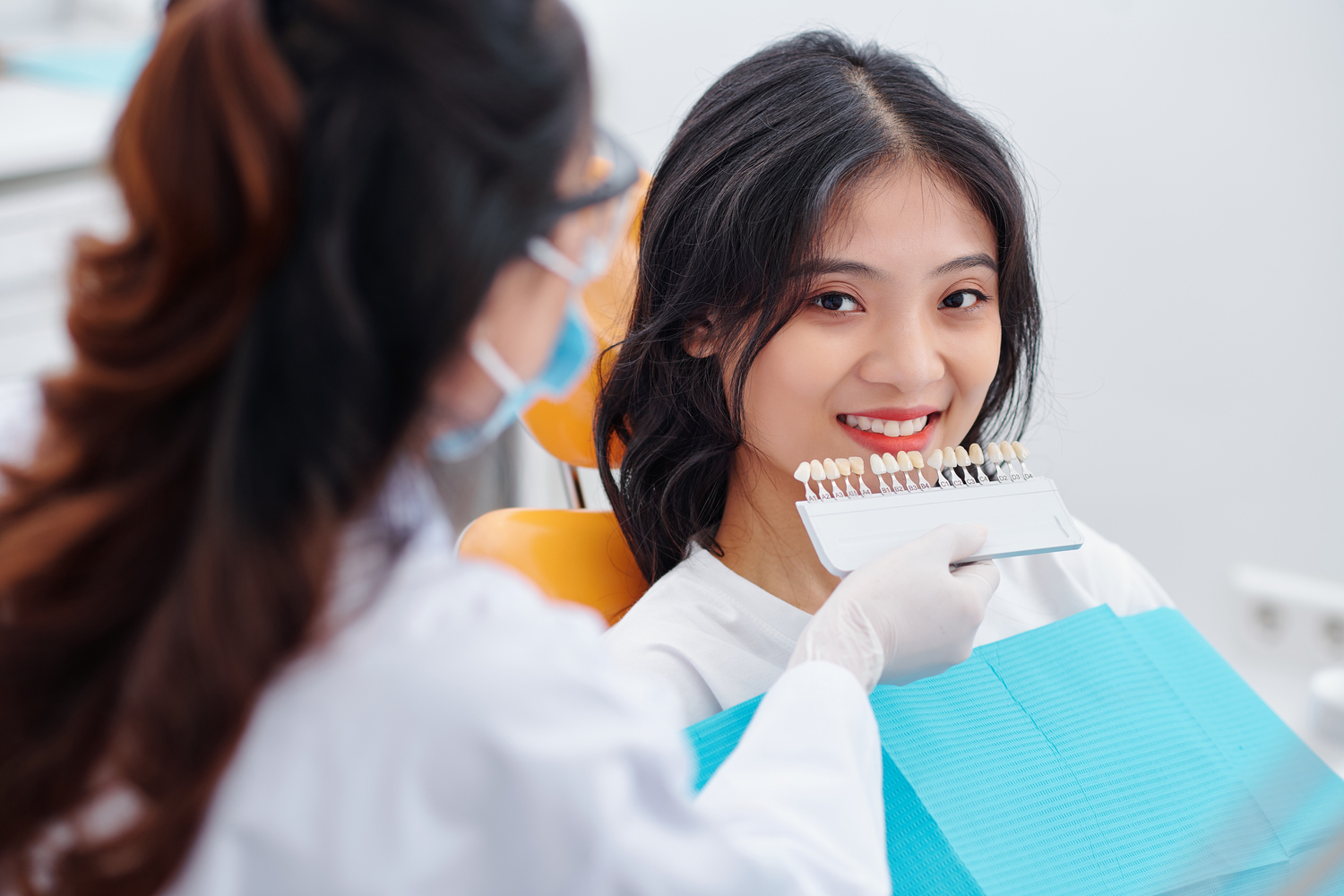 Dentist selecting patient's teeth color with palette in clinic