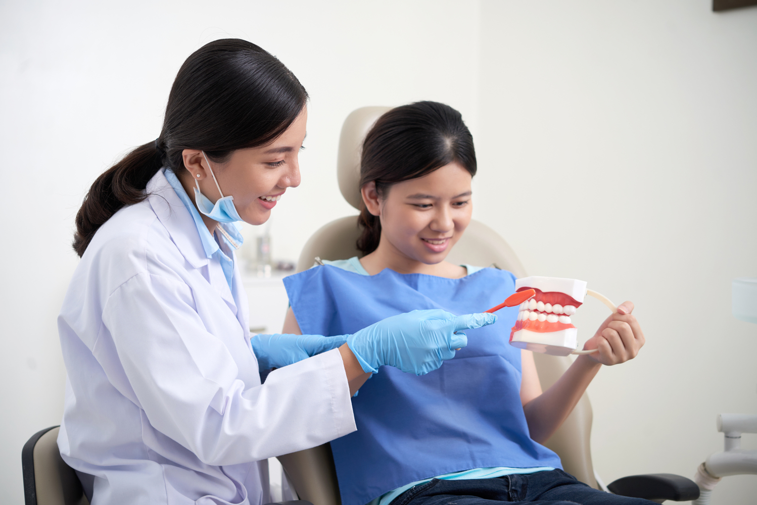 Dentist explaining her patient how to brush teeth