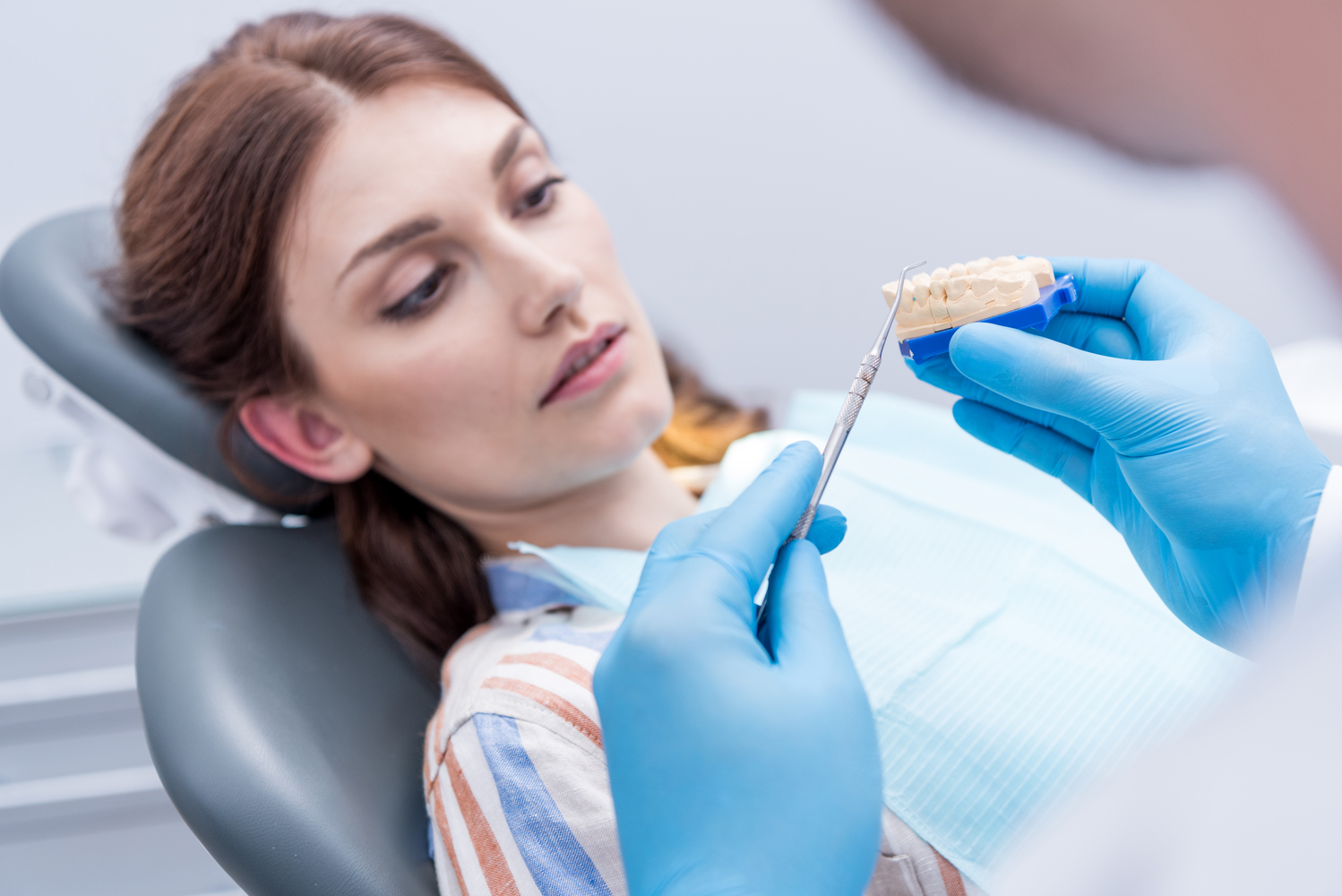 dentist showing dental mold to focused patient in dentist office