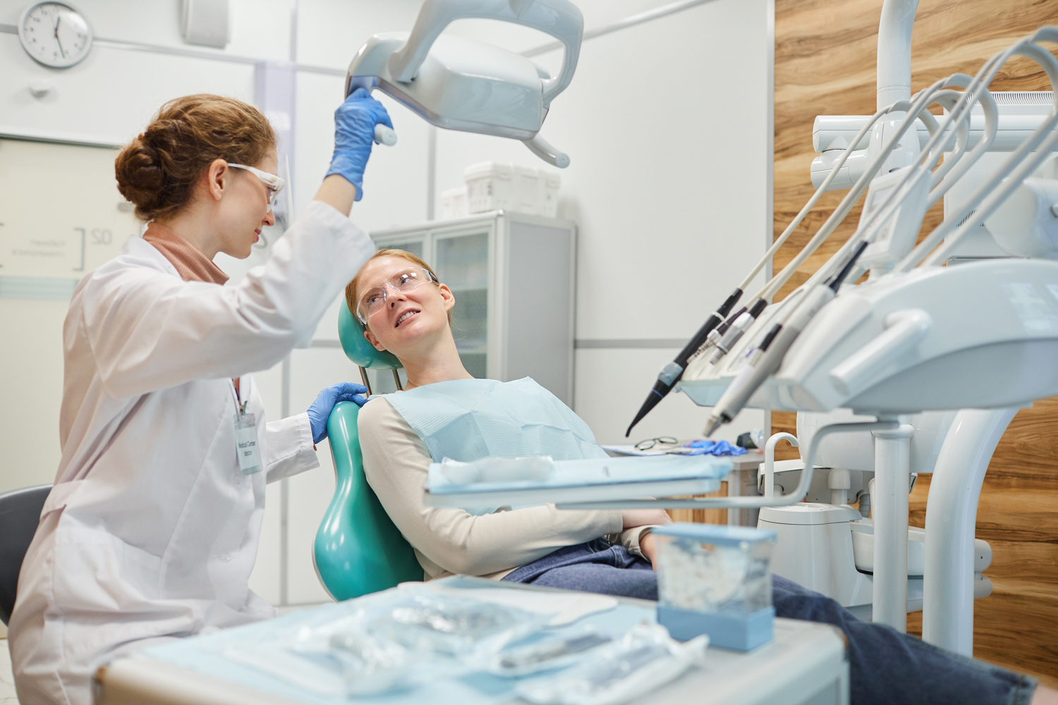 Patient lying on dental chair and talking to dentist during medical exam at clinic