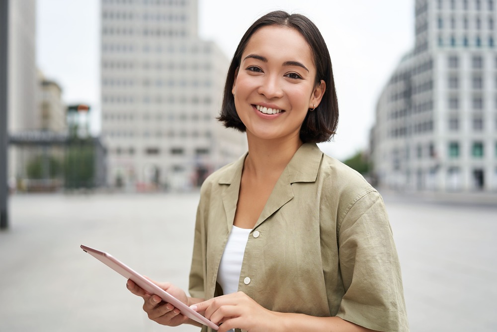 young-smiling-asia-woman-with-tablet-standing-on-2022-12-14-03-57-13-utc (1)