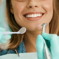 smiling-woman-sitting-in-medical-chair-while-denti-2021-09-03-14-07-45-utc-1-e1653633200669