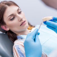 dentist showing dental mold to focused patient in dentist office