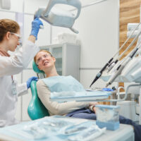 Patient lying on dental chair and talking to dentist during medical exam at clinic