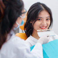 Dentist selecting patient's teeth color with palette in clinic